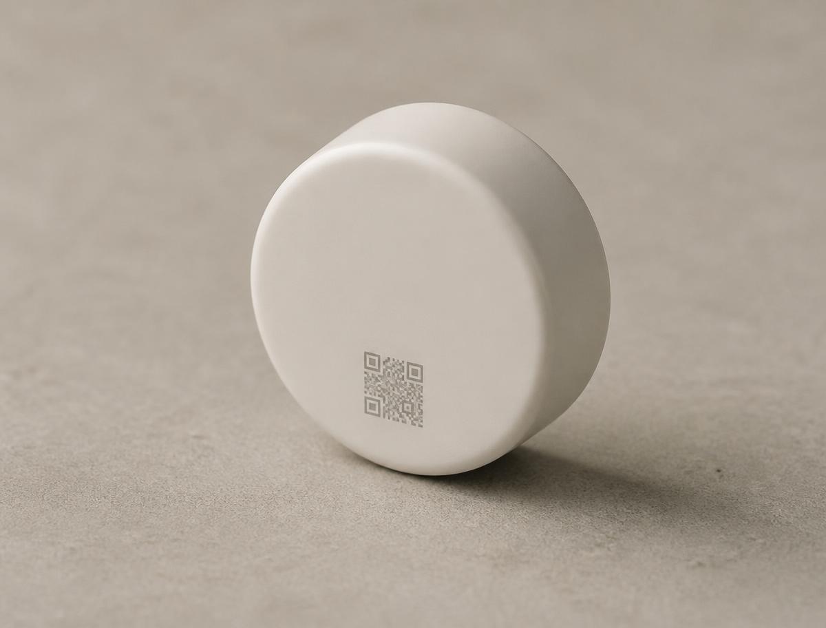 The Vokter sensor: a small off-white disc, 35 mm across, with a small QR code on its face